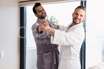 Happy gay couple dancing waltz in bathrobe