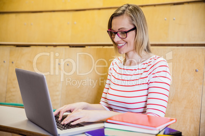 Happy female student typing on laptop