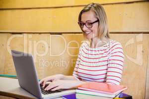 Happy female student typing on laptop
