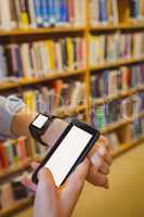 Brunette student using her smart watch and smartphone