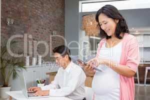 Smiling pregnant woman using tablet