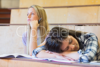 Bored student listening while classmate sleeping