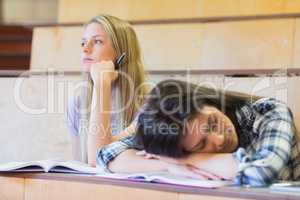 Bored student listening while classmate sleeping