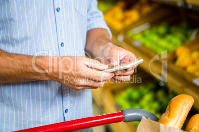 Man texting and grocery shopping