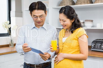 Happy expectant couple using tablet