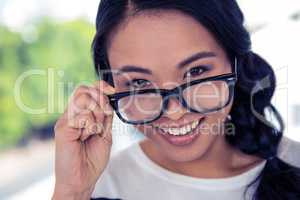 Smiling Asian woman holding eyeglasses