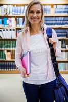 Female student holding textbooks in the library