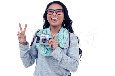 Asian woman holding digital camera and making peace sign with ha