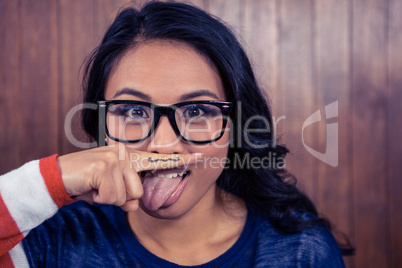 Asian woman with mustache on finger showing tongue