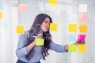 Asian businesswoman using sticky notes on wall