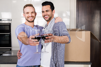 Smiling gay couple toasting with red wine