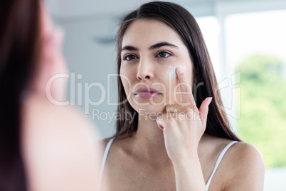 Brunette applying face cream