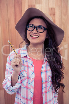 Smiling Asian woman with hat holding pencil