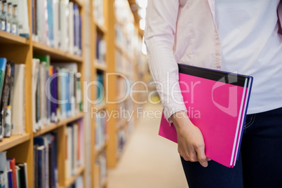 Female student holding textbooks in library