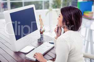 Asian woman on computer with finger on chin