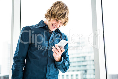Happy hipster businessman laughs looking at his phone