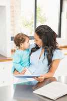 Smiling brunette holding her baby and using tablet