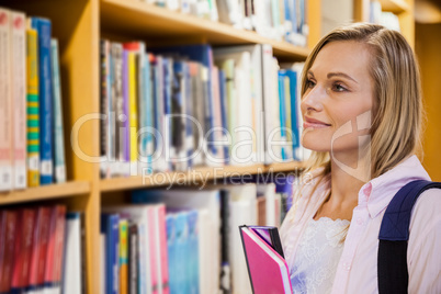 Female student picking a book in the library