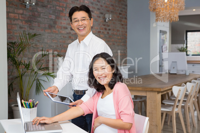 Happy man showing tablet to his pregnant wife