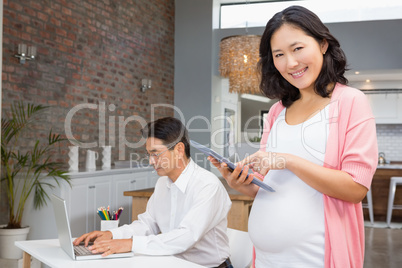 Smiling pregnant woman using tablet