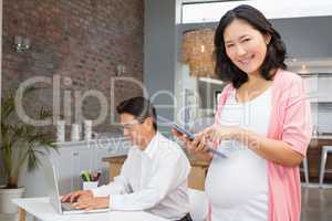 Smiling pregnant woman using tablet