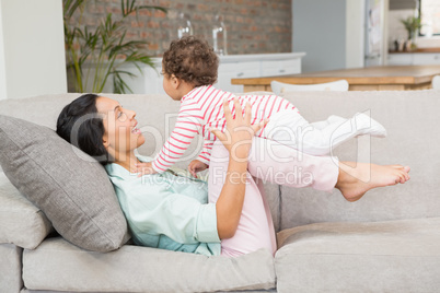 Smiling brunette playing with her baby