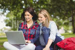 Smiling students using laptop