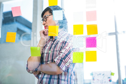 Thoughtful creative businessman looking at sticky notes