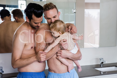 Happy gay couple holding their child