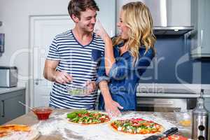 Smiling couple preparing pizza