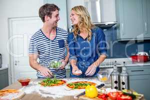 Smiling couple preparing pizza