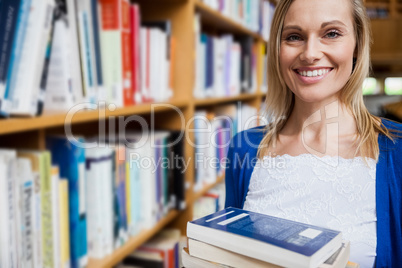 Happy female student taking books in the library