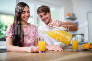 Handsome man pouring orange juice in a glass