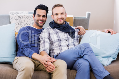 Gay couple holding hands on couch