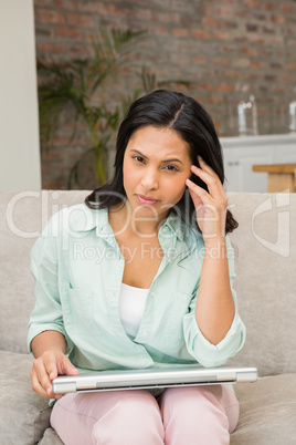 Worried brunette with closed laptop on her legs