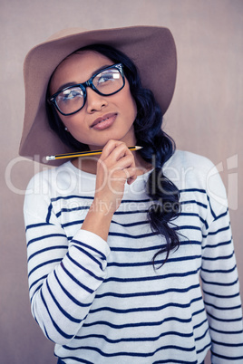 Smiling Asian woman with hat holding pencil