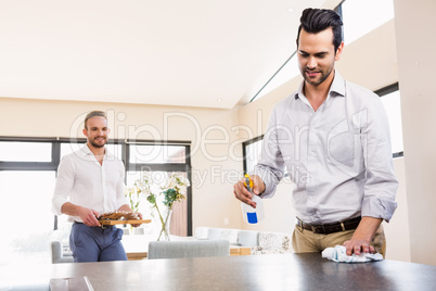 Smiling gay couple cleaning living room