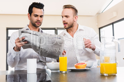 Concentrated gay couple reading newspaper