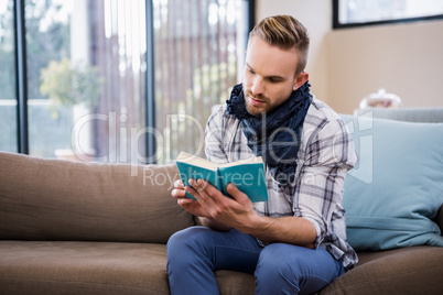 Handsome man reading a book on the couch