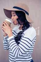 Attractive woman with hat holding disposable cup