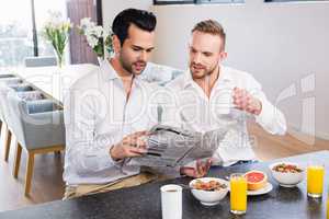 Smiling gay couple reading newspaper