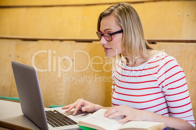 Happy female student using laptop and reading