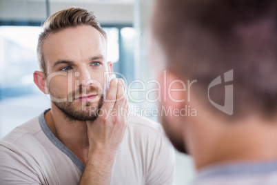 Concentrated man shaving his beard