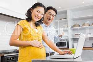 Happy expectant couple using laptop