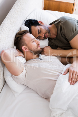 Happy gay couple sleeping together on bed