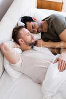 Happy gay couple sleeping together on bed