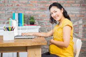 Smiling pregnant woman using laptop