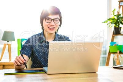 Smiling hipster businessman using laptop and graphic tablet