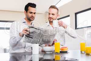 Smiling gay couple reading newspaper