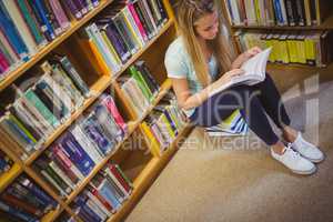 Blonde student reading while sitting on books